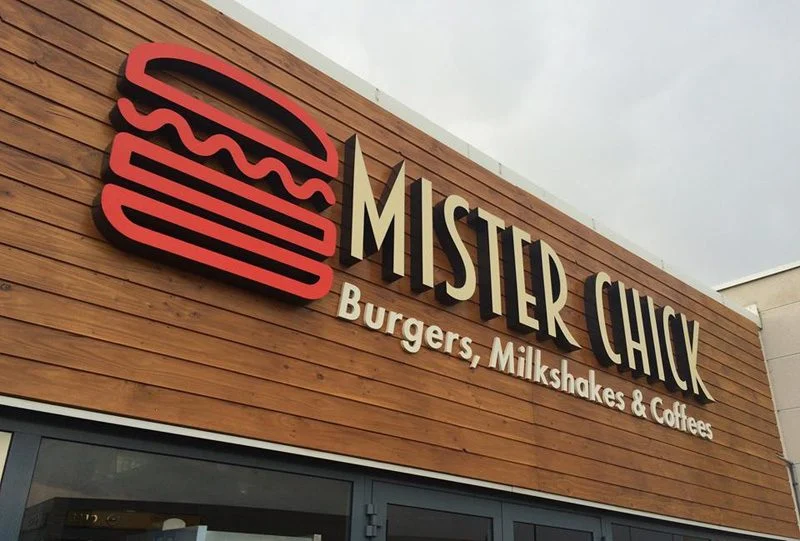 Logo burger rouge et lettres Mister Chick sur une façade en bardage bois