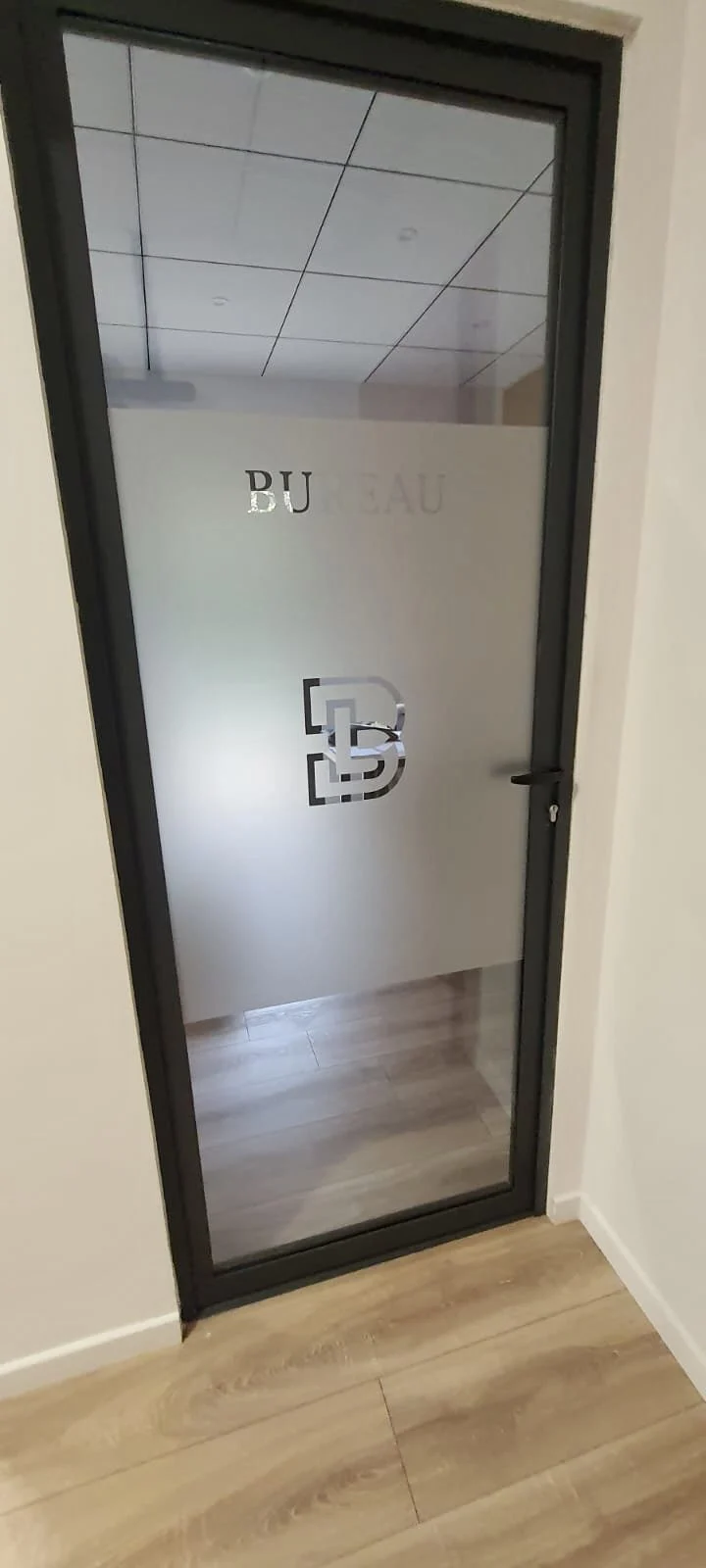 Porte vitrée noire marquée Bureau et logo découpé