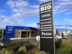 Totem extérieur présentant plusieurs enseignes d’un pôle commercial bio