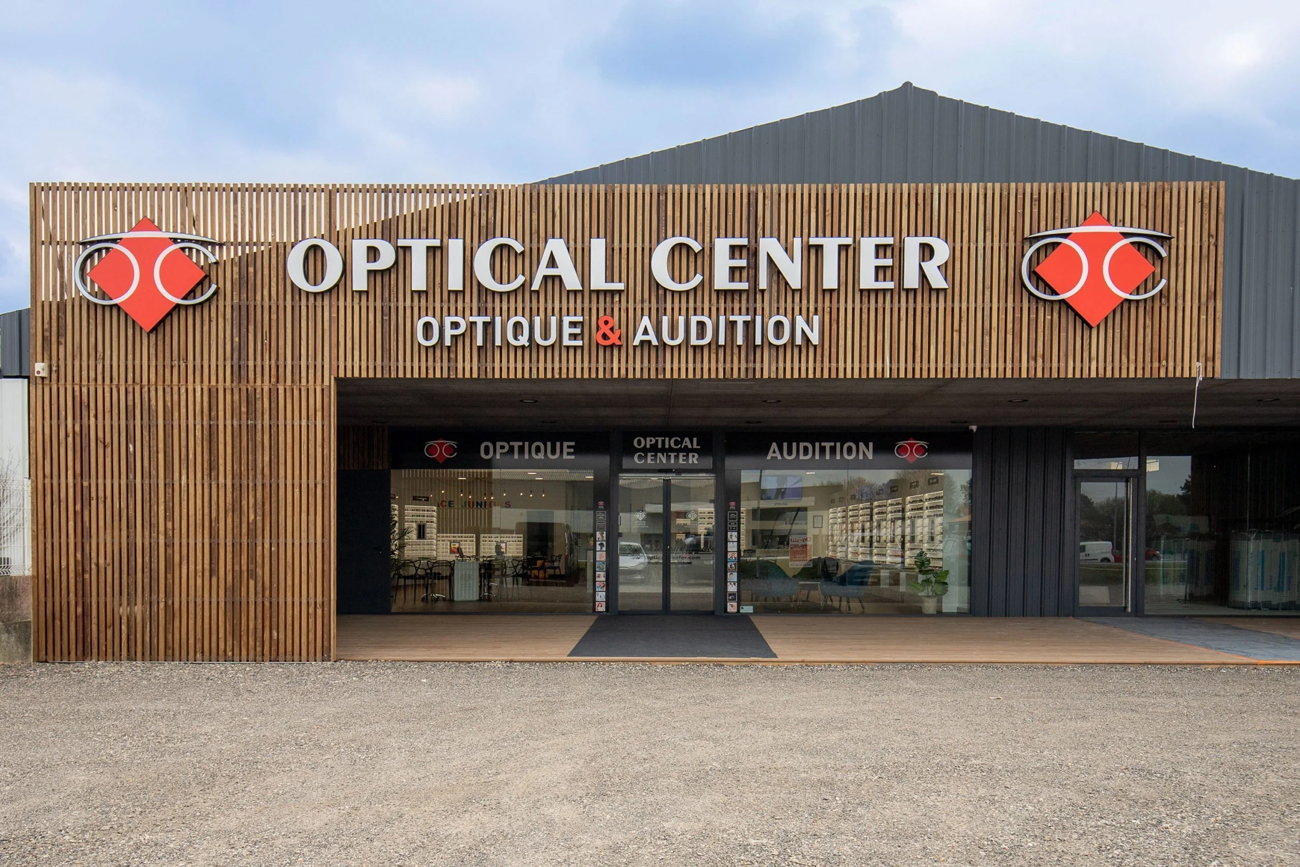 Lettres relief Optical Center et logos rouges sur un claustra bois