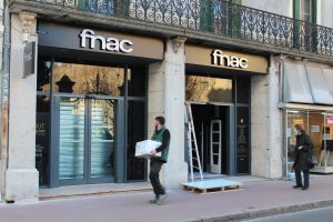 Deux logos Fnac en lettres relief au-dessus de portes vitrées