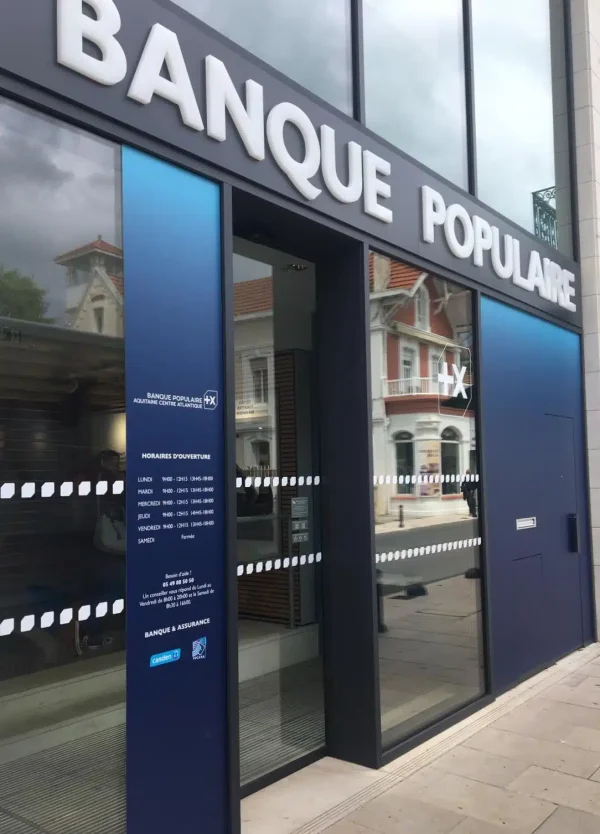 Grandes lettres blanches Banque Populaire fixées sur un bandeau gris