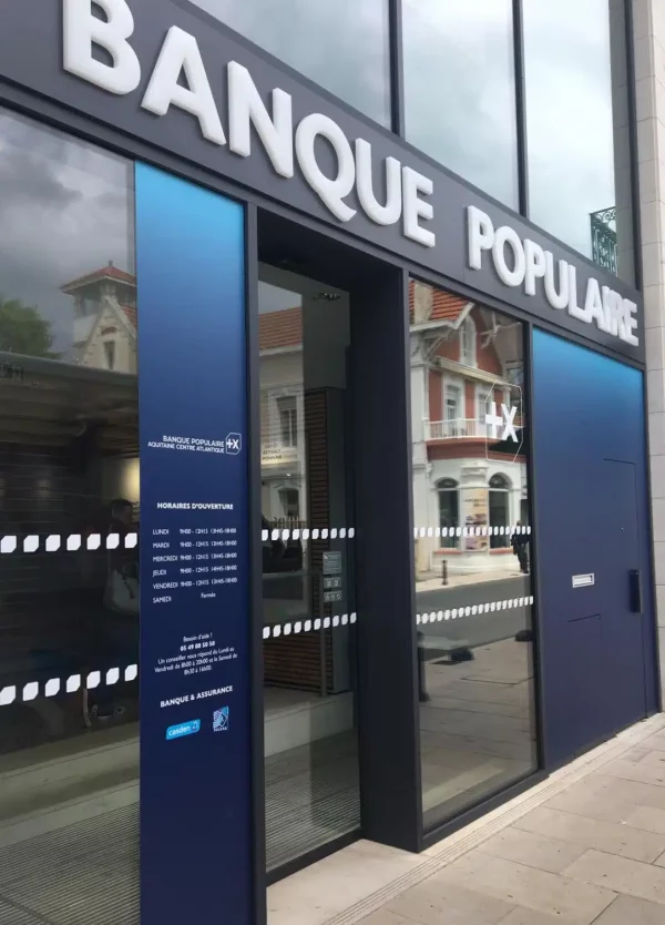 Grandes lettres blanches Banque Populaire fixées sur un bandeau gris