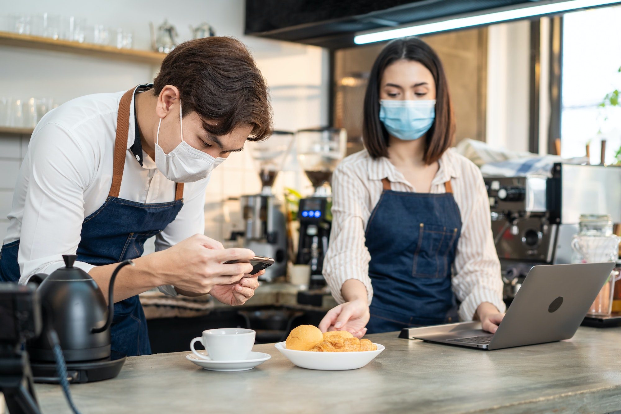 Asian barista couple enjoy doing digital marketing in cafe restaurant 