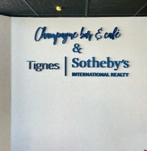 Lettres découpées Champagne Bar et Café et Tignes Sotheby’s sur un mur intérieur