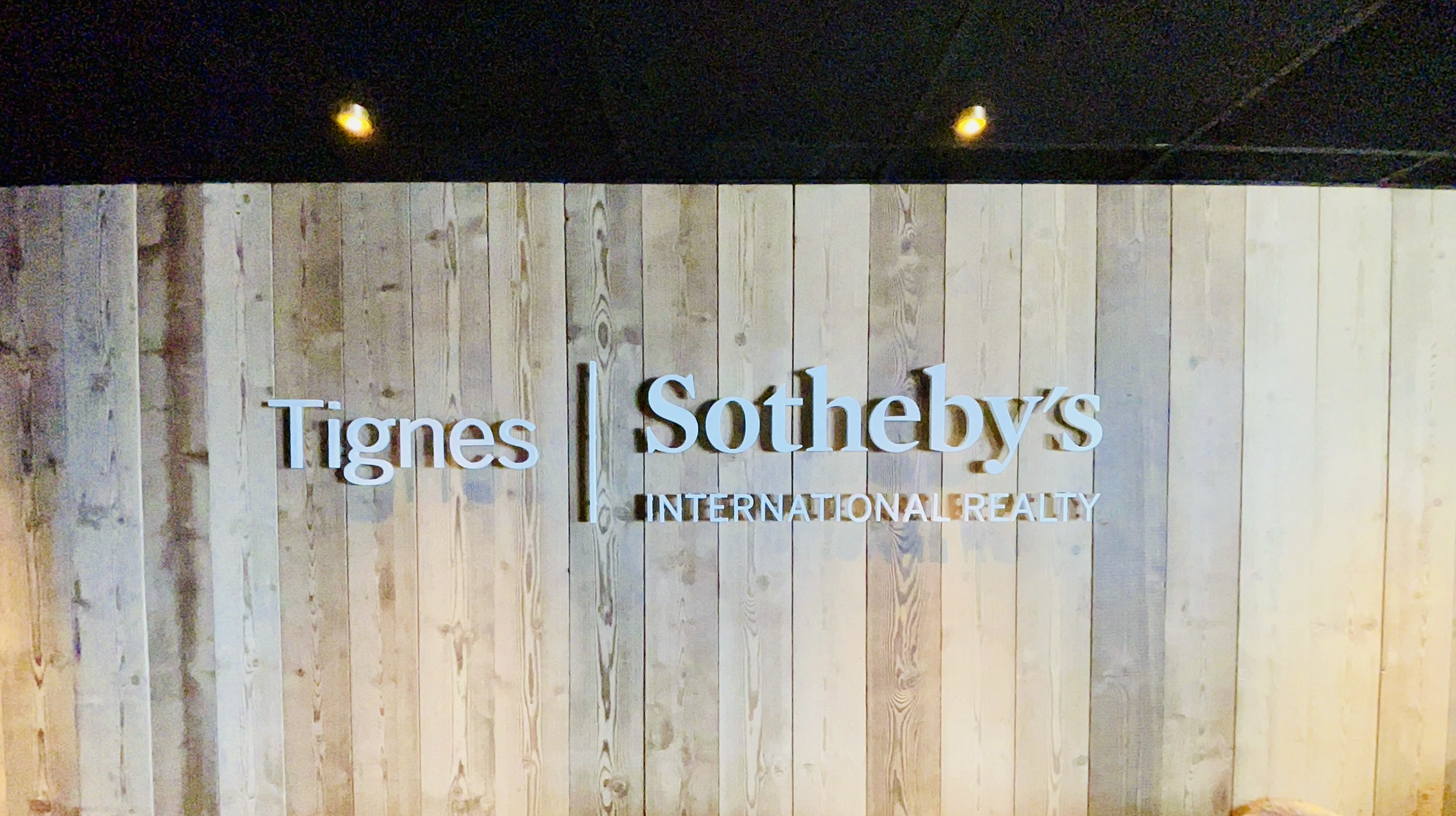 Lettres découpées blanches sur habillage mural en bois – totem lumineux