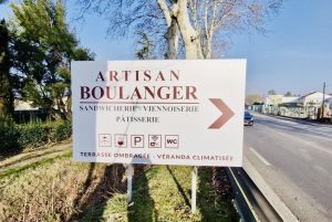 Panneau en bord de route indiquant un artisan boulanger vers la droite