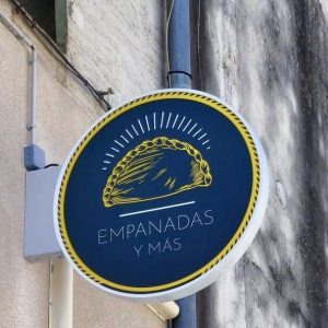Enseigne ronde « Empanadas y más » avec un empanada stylisé