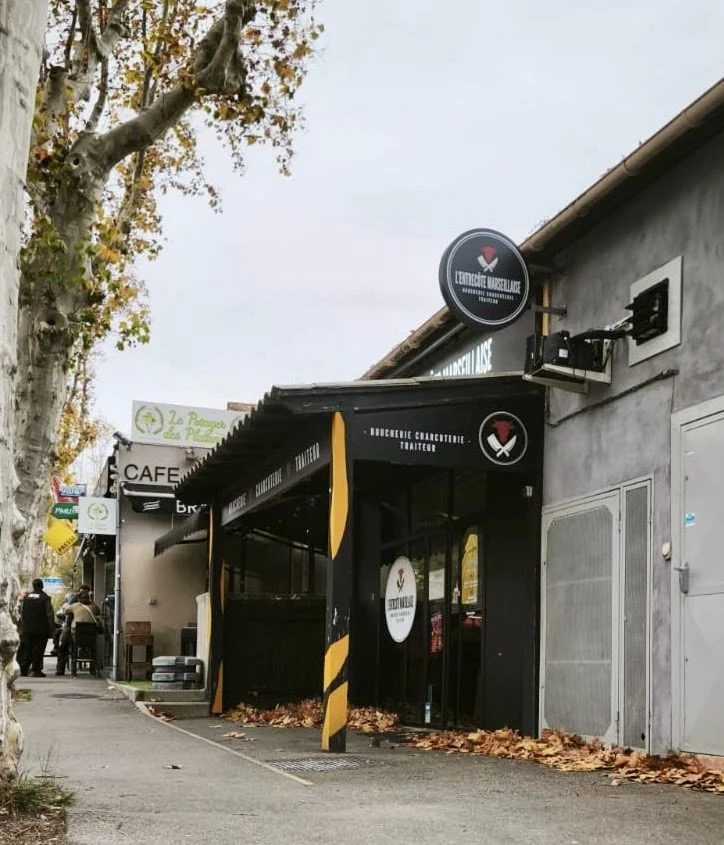 Enseigne drapeau ronde et façade de L'Entrecôte Marseillaise vues de la rue